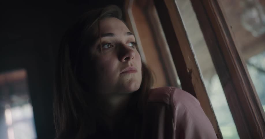 A woman is looking out of her window