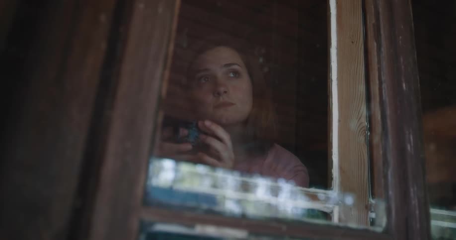 A woman sitting in a window with a mug
