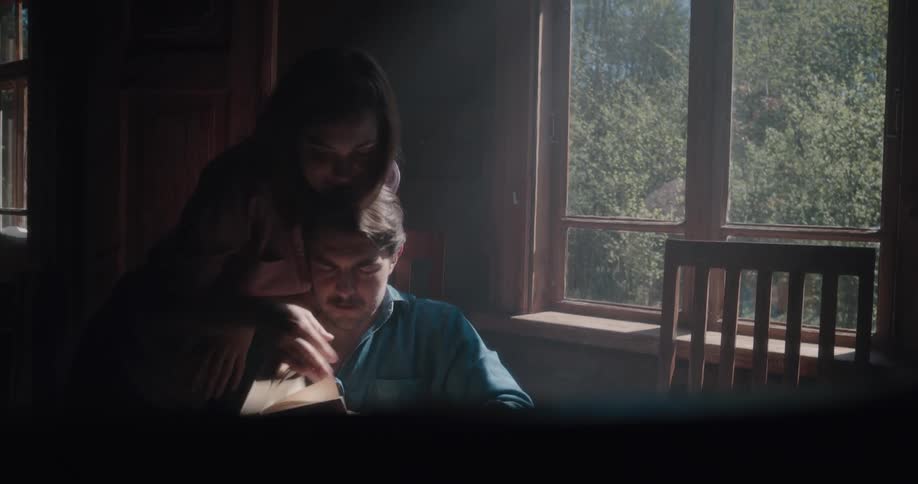 Young couple playfuly reading a book on a table at home