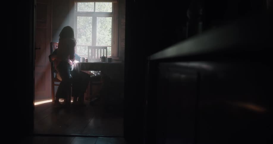 A man and a woman in a room hugging with a wall and window in the background