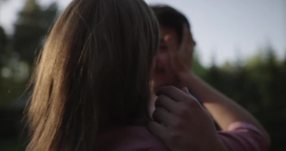 A man arrives at a house and runs to a woman and they hug and kiss and then walk to the house