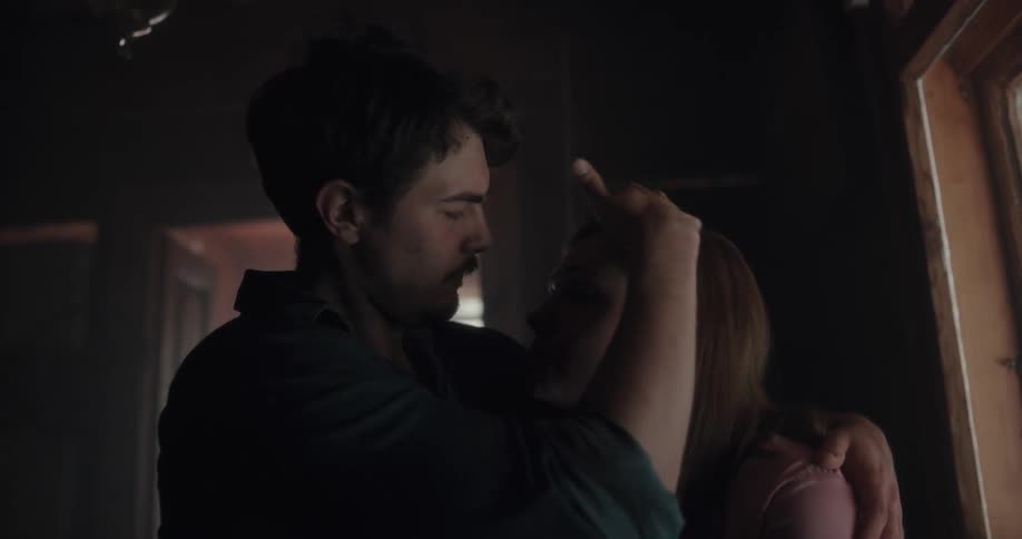 A man holds a woman close to him in a hug while caressing her hair