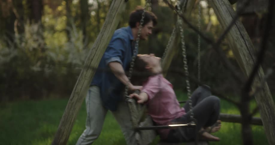 A man pushes a woman on the swing