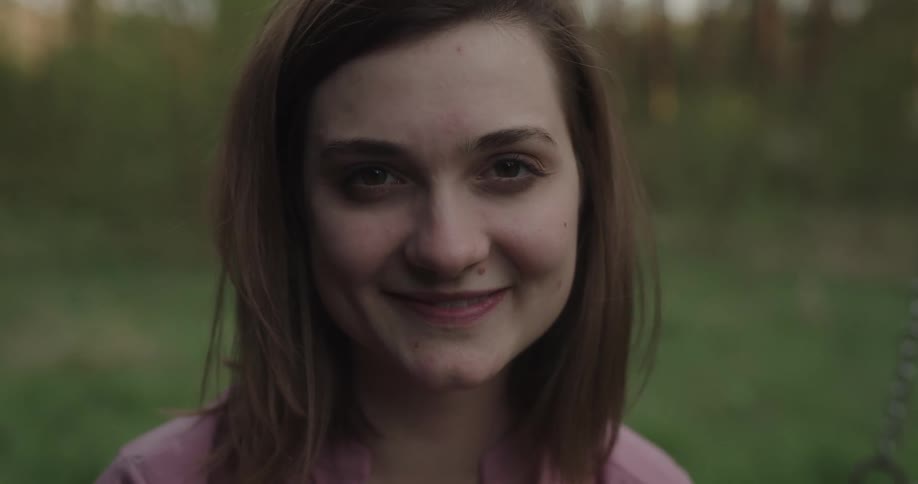 A young woman stands outside and smiles and laughs