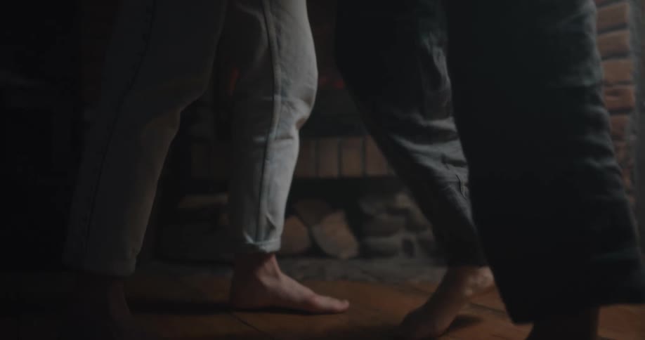 The feet of a man and woman as they dance in front of a fireplace
