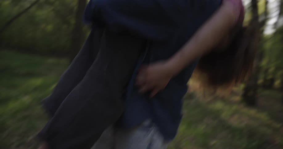 A man and woman hug and play around in the forest
