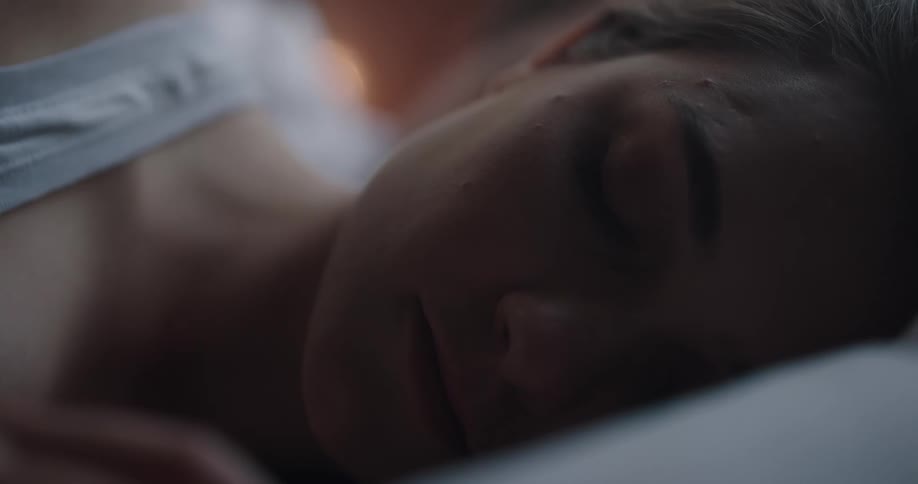 A woman sleeping in a bedroom laying on a bed with a pillow