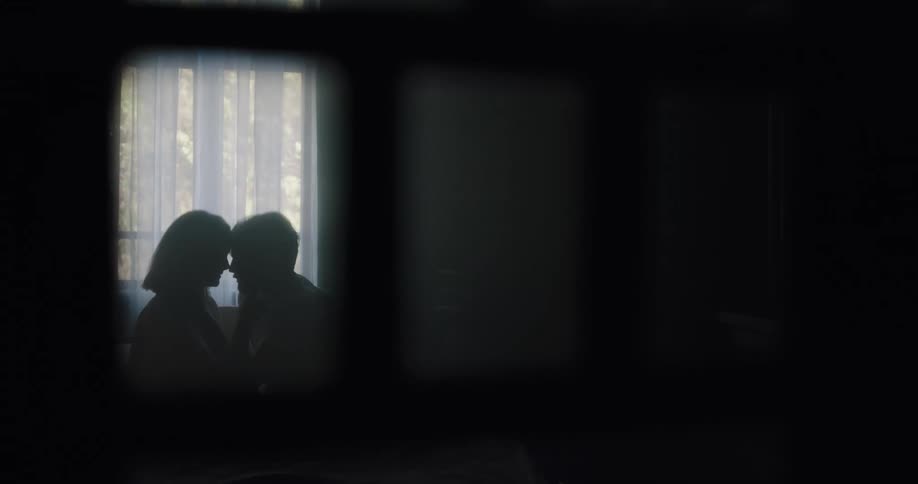 A man and woman kissing each other in a room