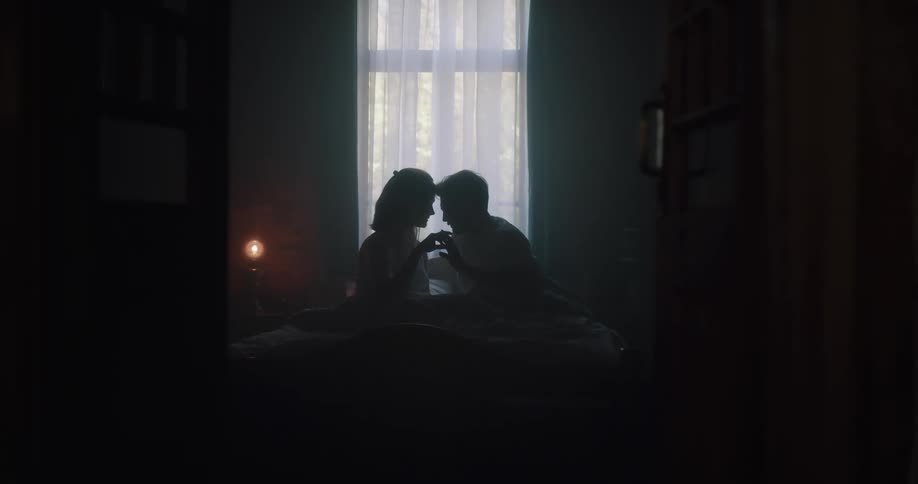 A the silhouette of a man and woman can be seen sitting close together in front of a window