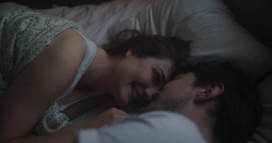 Couple lie down cuddling and smiling in bed