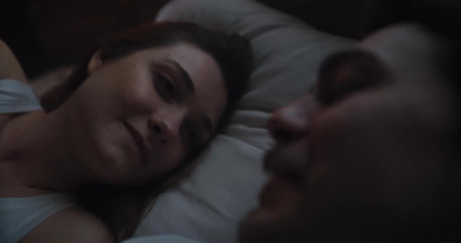A man caresses his girlfriends face as they lie in bed