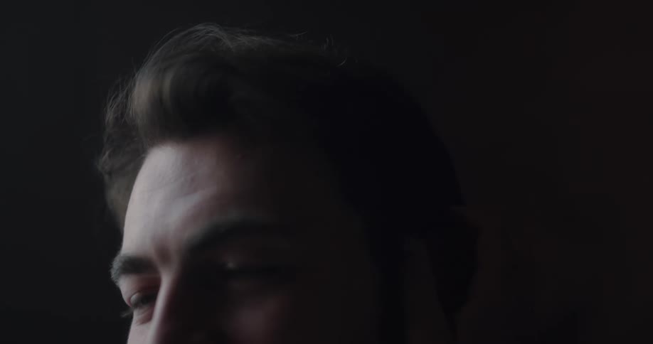 A man smiles as his partner caresses his head and hair