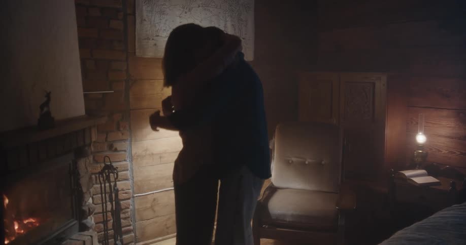 Couple kissing passionately near a fireplace in a dimly lit room