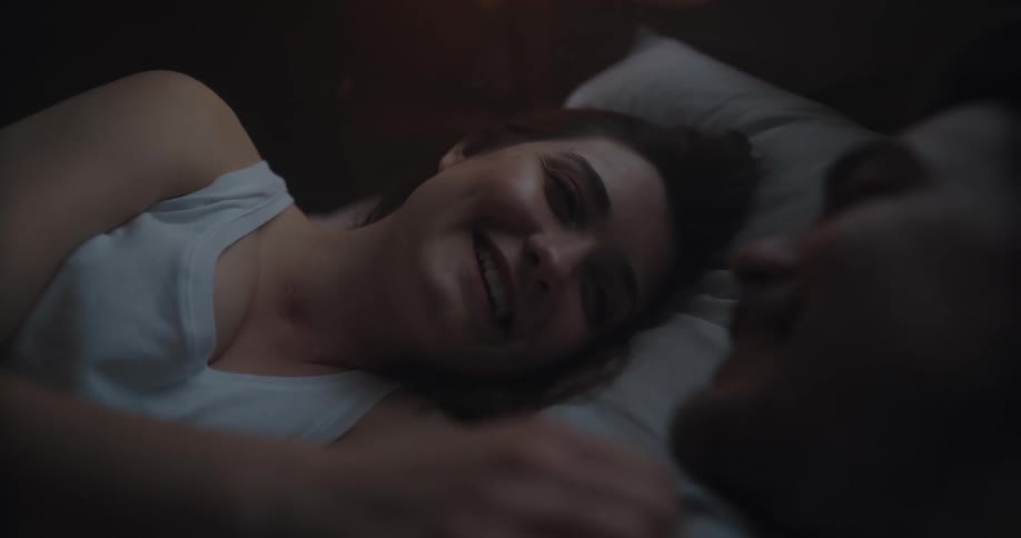 Husband and wife are laying in bed together at night