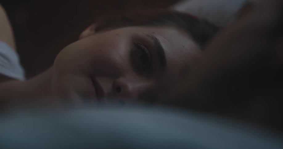 Woman resting in bed talking to her couple inside a dimly lit bedroom
