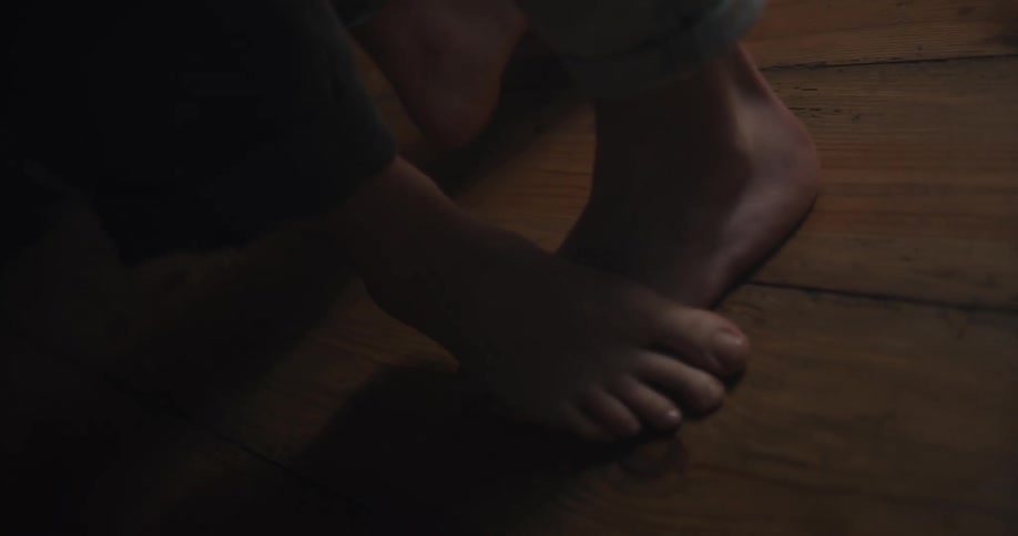 Person stands on anothers feet on wooden boards while dancing