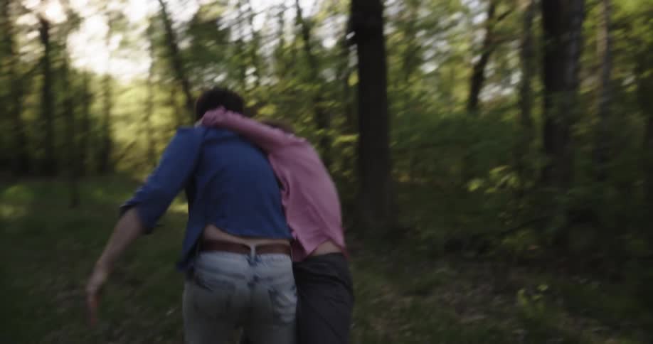 Two people running and jumping on each other in a forest