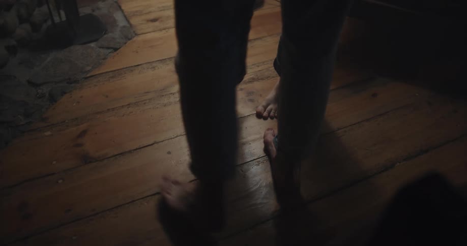 A man and woman slowly dance together in bare feed while indoors