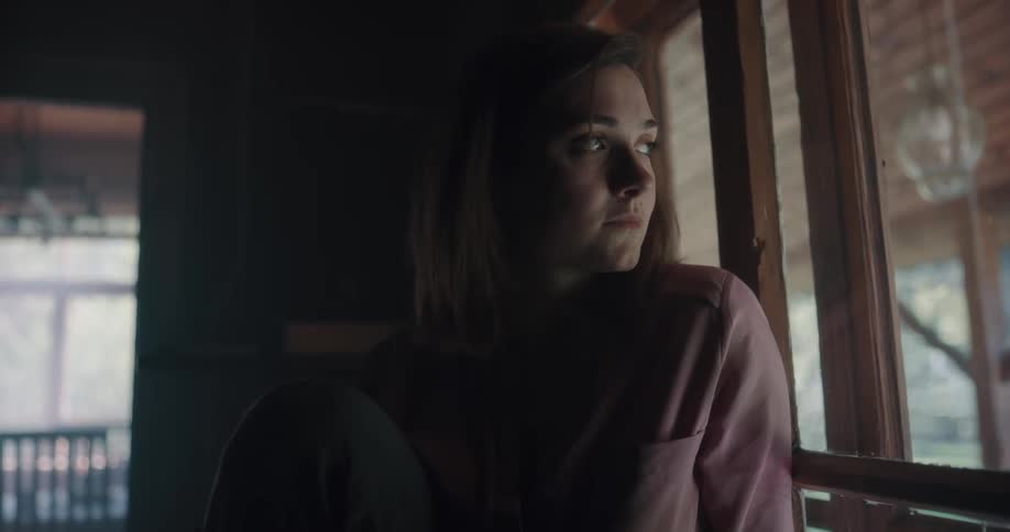 A woman sitting in a room staring out of a window