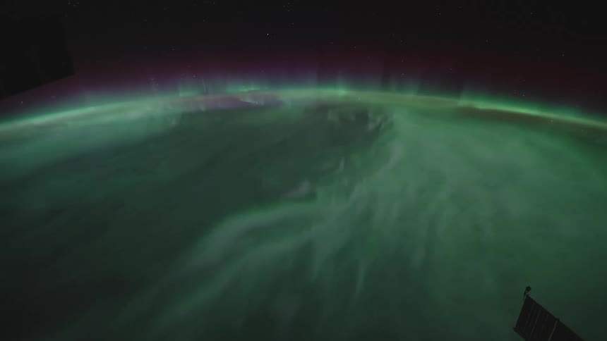 Green light glows and ripple above the earths curved surface seen from space