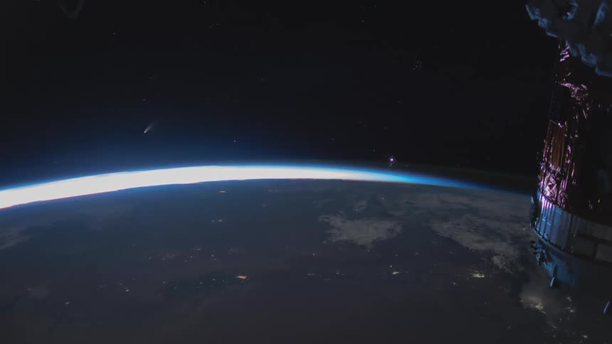 A satellite moves toward the glowing daylight at the curve of earth