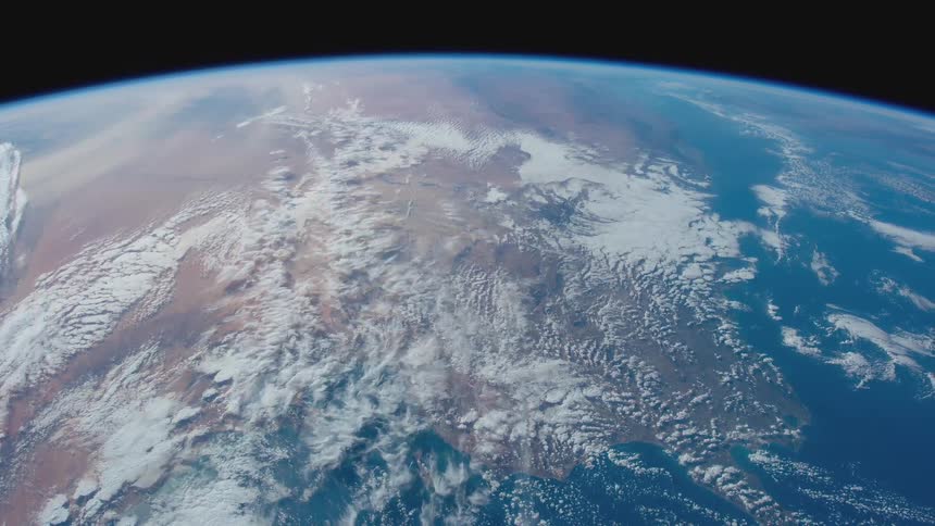 Clouds float over desert and water on globe shining blue against blackness of space