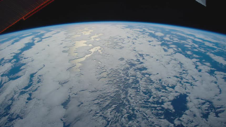 Sun reflect off planet as blue of ocean and white of ice and clouds rotate under solar panels