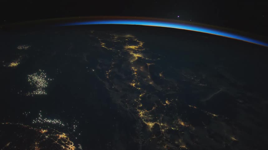 City lights shine on globe as atmosphere on horizon shines blue against blackness of space