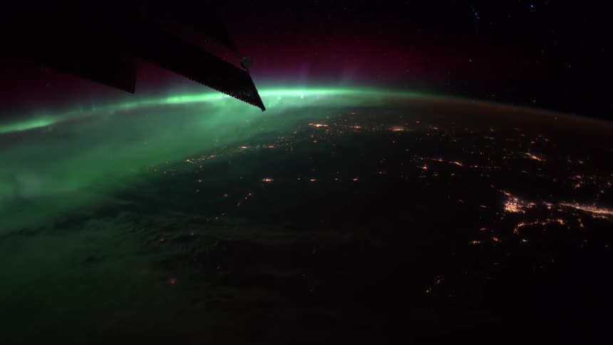 Atmosphere glows bright on planet covering part of earth lights under solar panels ofstation
