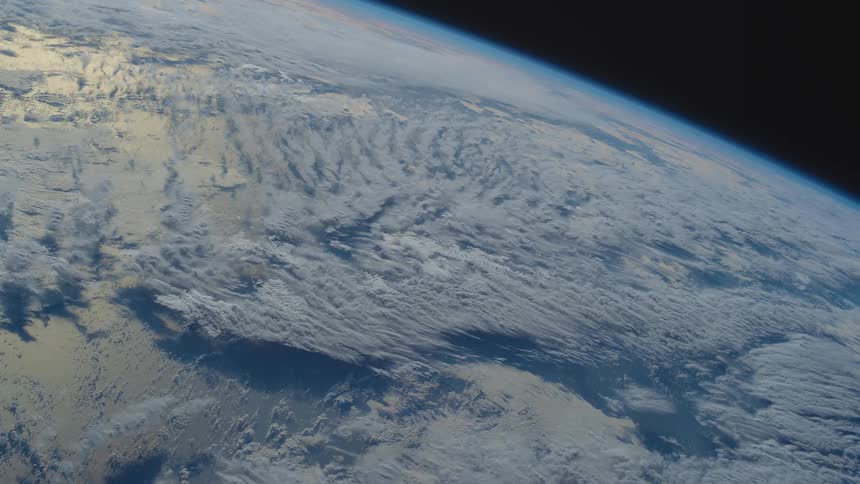White of clouds and snow reflecting sunlight contrast with blue of oceans against the blackness of space