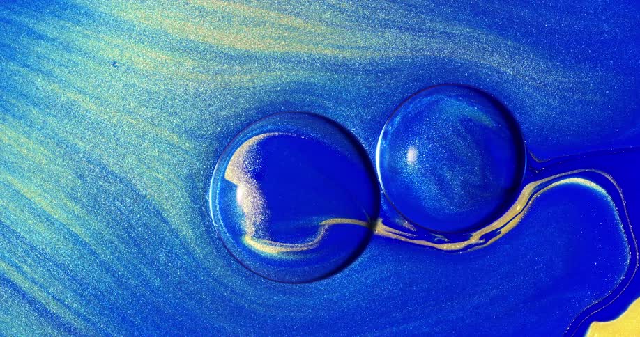 A blue and yellow liquid with glitter flows around two blue circles