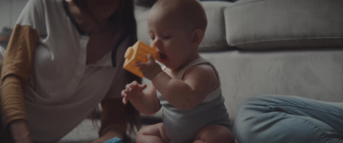 A baby plays with blocks in front of the couch