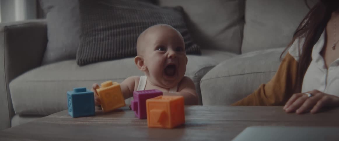 Happy baby playing with colorful plastic blocks over a table in the living room