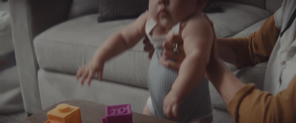 A woman and baby play on the floor with baby toys