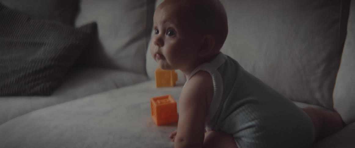 A baby in a room on a couch with blocks and cushions