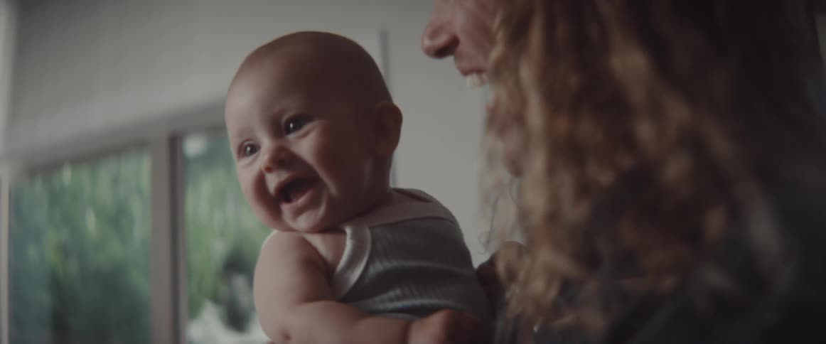 A woman laughs as her infant son starts laughing
