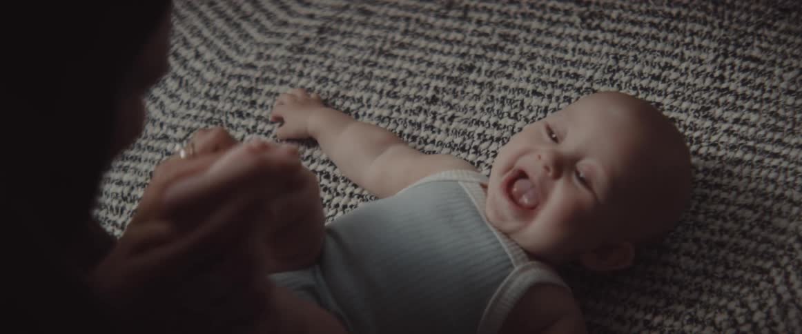 A baby laughs as her mother tickles and kisses her feet