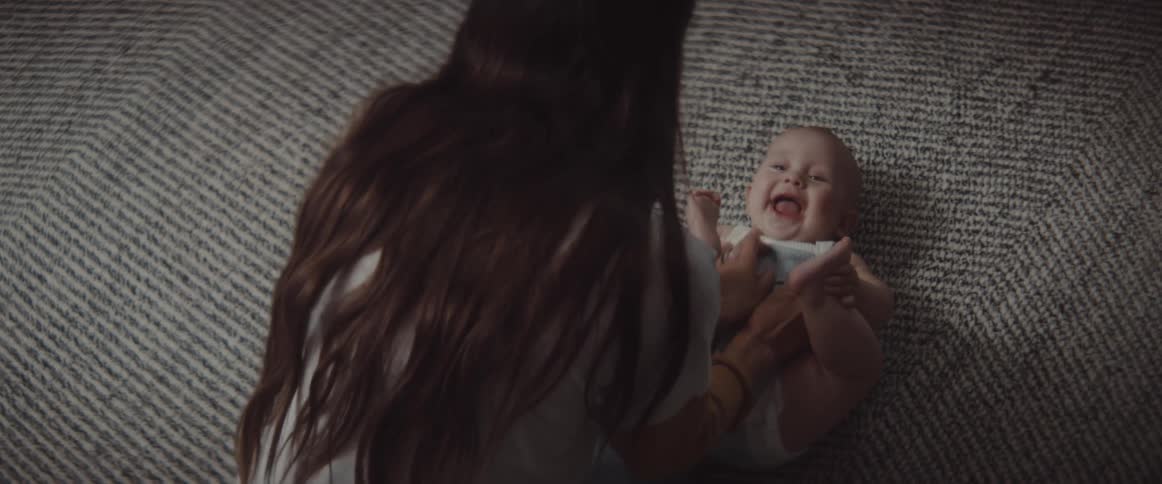 A woman in a room playing with a baby on the floor