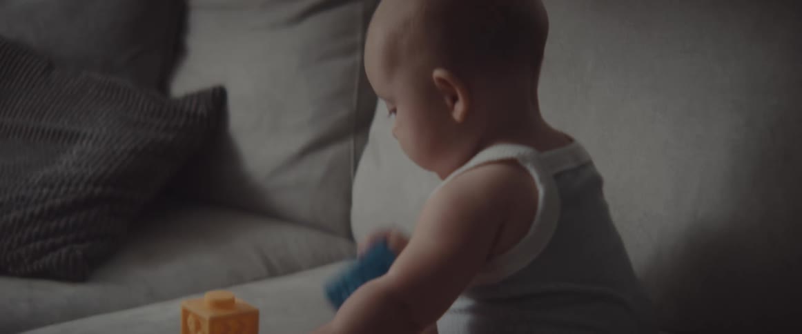 A baby in a room on a couch with blocks and cushions