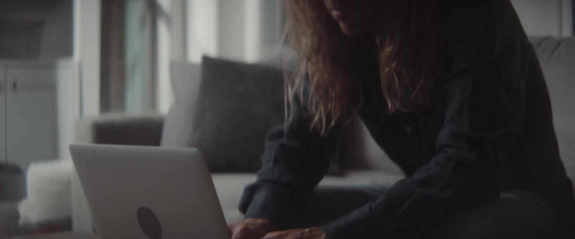 A man sits on a couch at home and types on a laptop