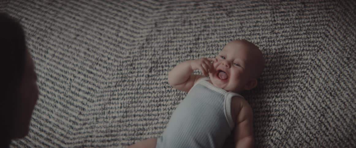 A woman tickles her baby who laughs
