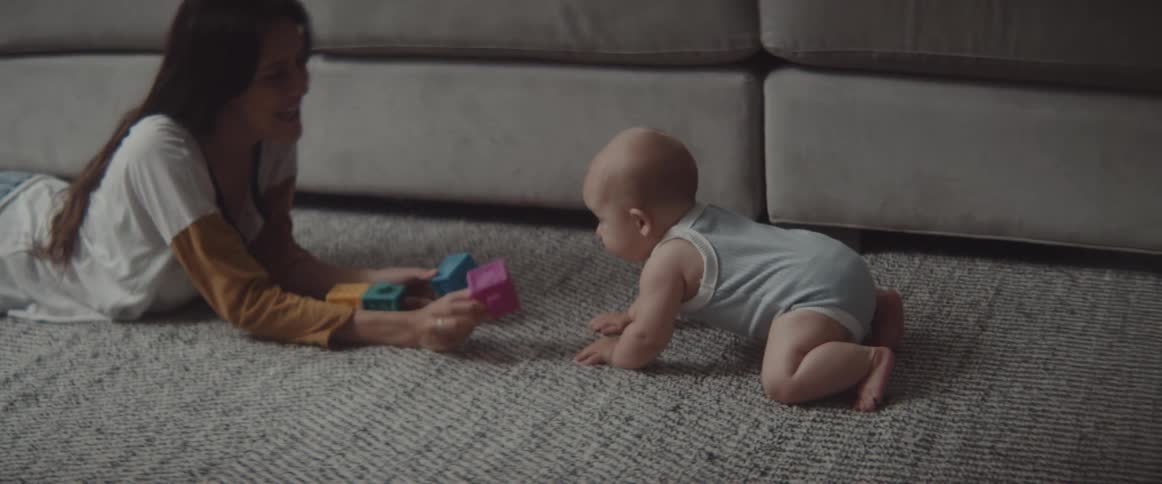 A baby is playing with blocks with his sister