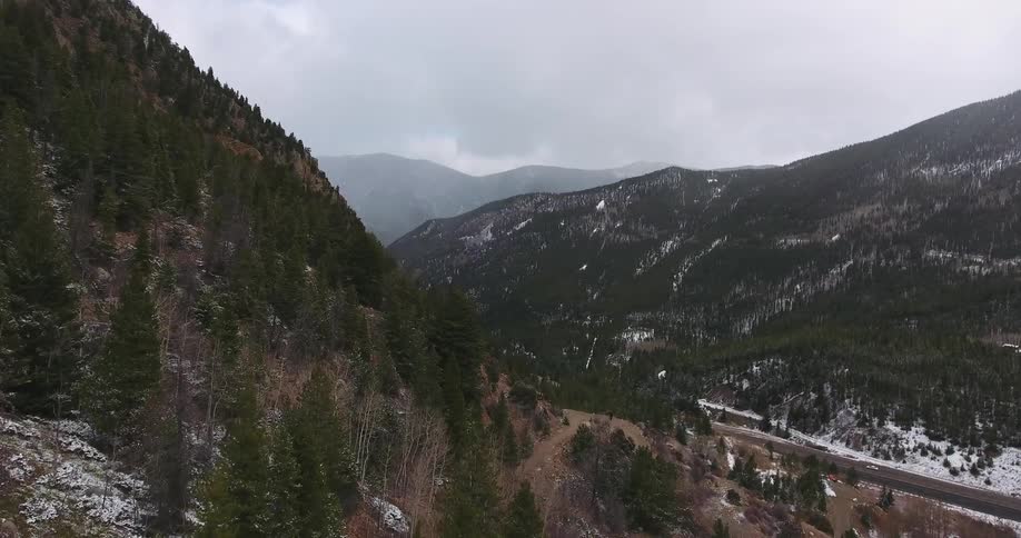 Aerial view of traffic moving down a road in a valley between two mountains
