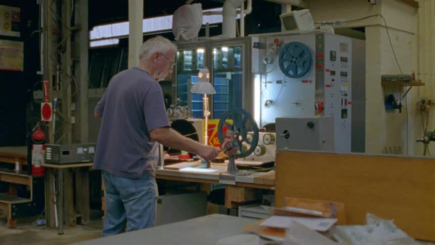An elderly man spins film on to a projector