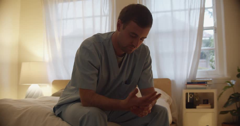 Young male nurse sitting on the bed at home in the morning