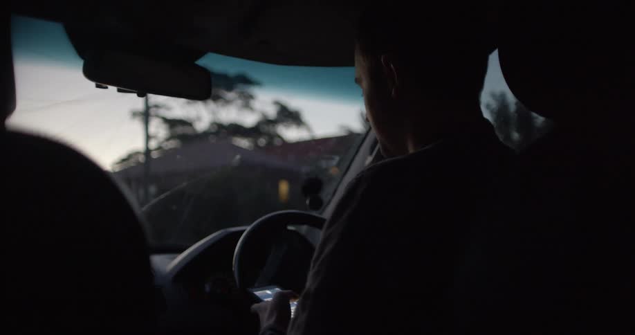A man driving his car looks down at his cell phone