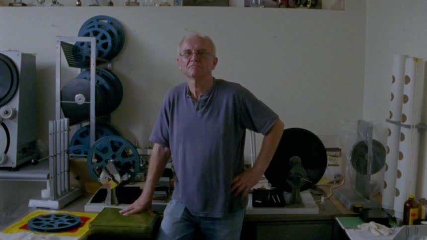 An older man standing in front of reels of film