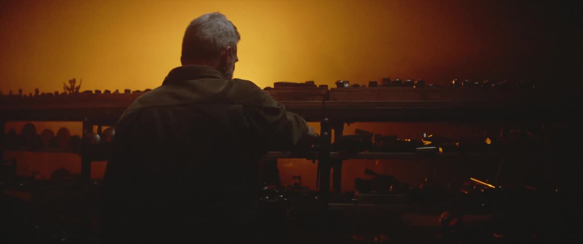 A bright light moves left and right as a man selects items from a large shelving unit in a warehouse