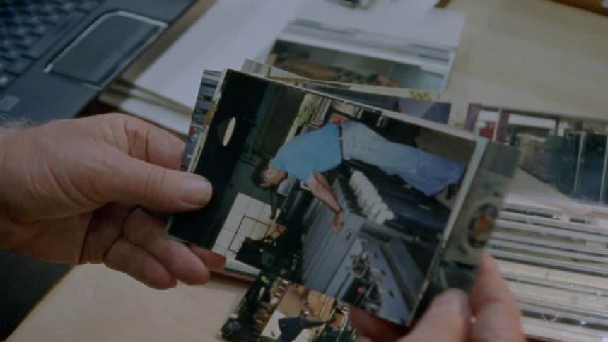A person with a wristwatch in a room sitting at a table looking through pictures