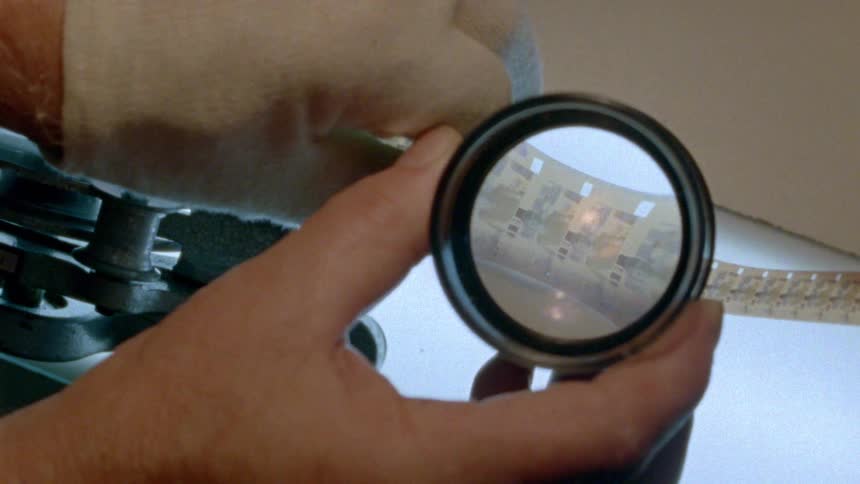 Person examines interlocking pieces with magnifying glass